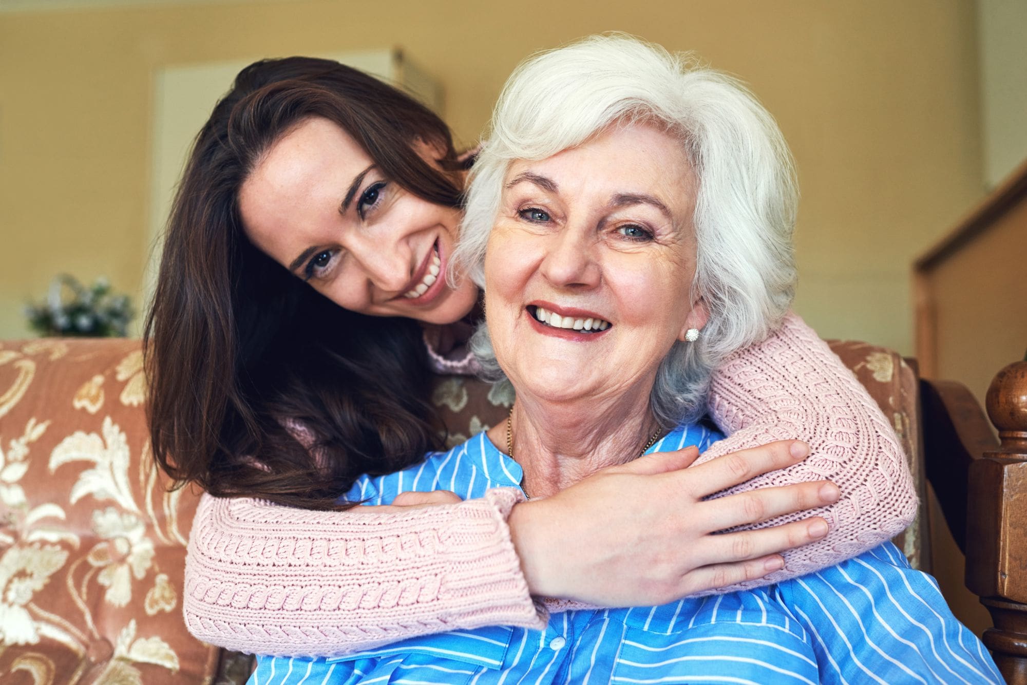 Assisted Living resident with granddaughter who has is hugging her from behind